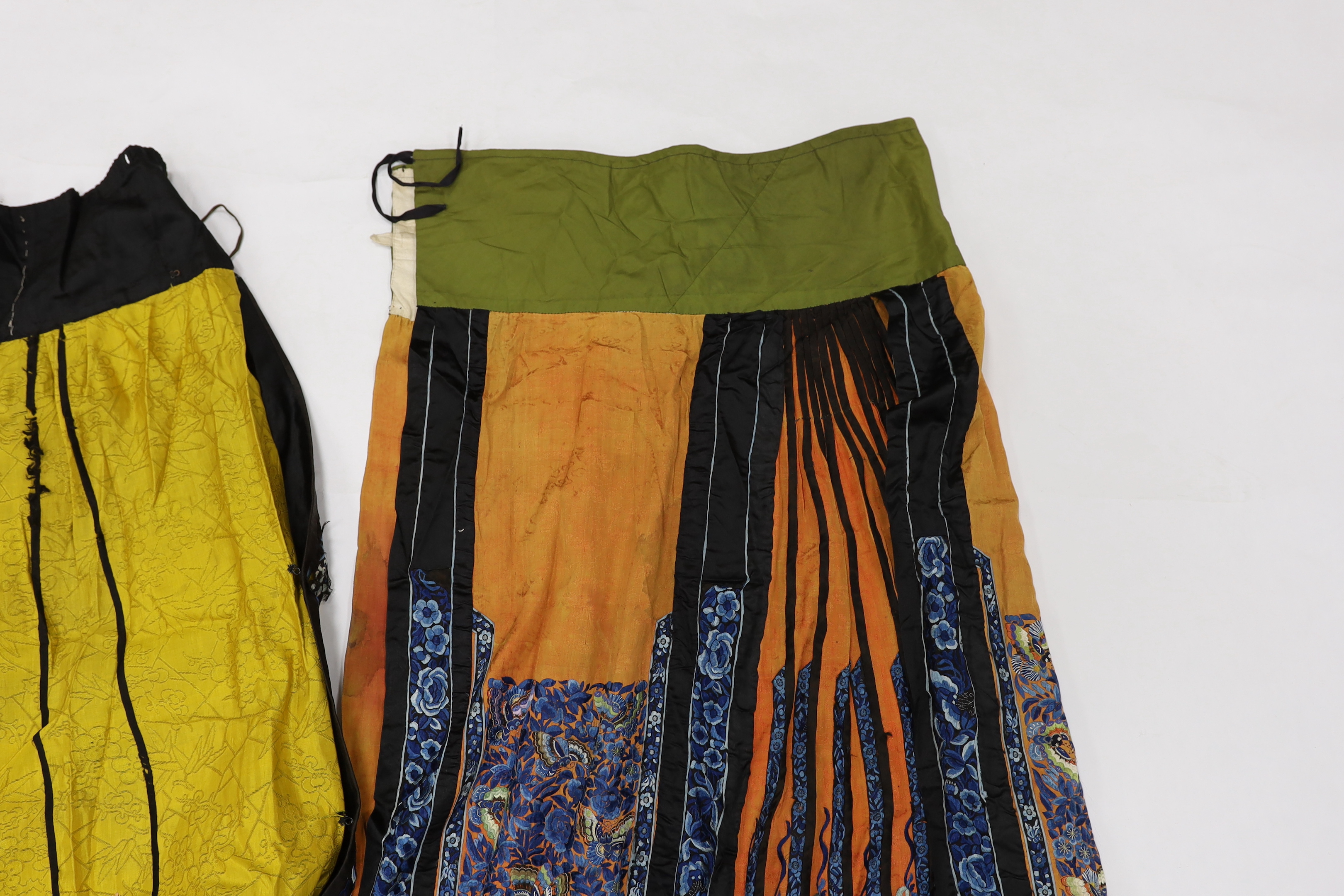 A late Chinese Qing yellow silk damask wedding skirt, with polychrome coloured silk embroidery, together with a similar coral silk damask blue embroidered wedding skirt